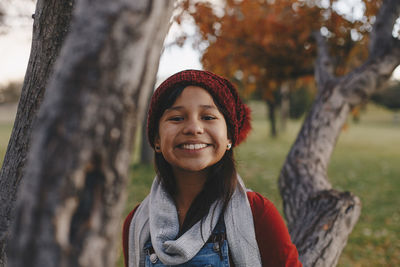 Portrait of a smiling young woman near a tree in fall