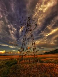 Electricity pylon on field against sky during sunset