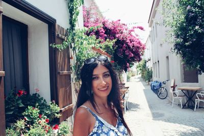 Portrait of beautiful woman smiling while standing by flower plants