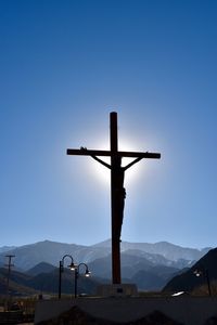 Cross on mountain against clear blue sky