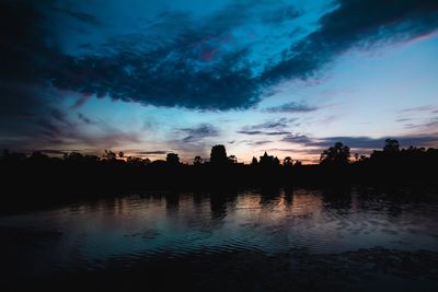 Silhouette trees by lake against sky during sunset