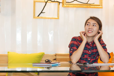 Portrait of woman sitting on table against wall