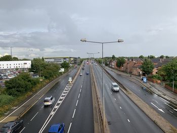 Vehicles on highway in city against sky