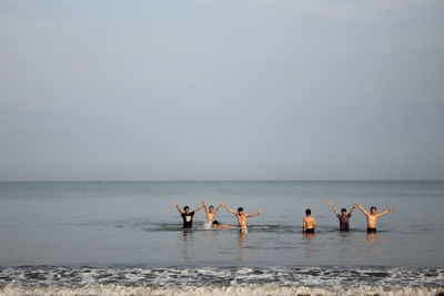 Group of people on beach against clear sky