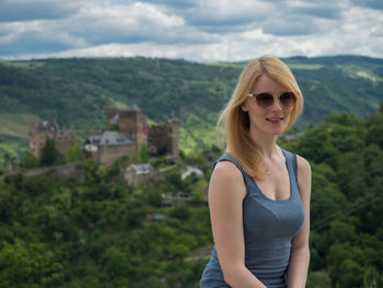 Portrait of smiling young woman standing against green landscape