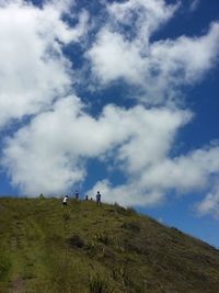 Low angle view of people walking on mountain against sky