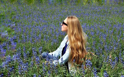 Woman wearing sunglasses relaxing in lupine field