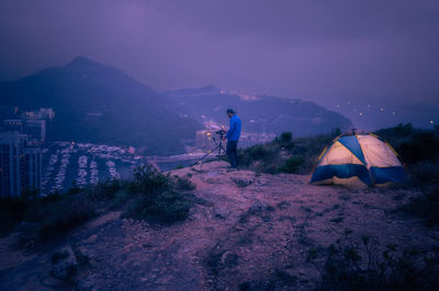 Man traveler taking photo on top of mountains near of tent camping