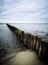 Wooden posts on beach against sky