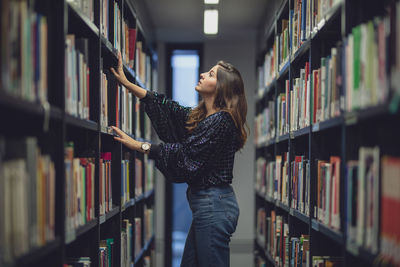 Side view of young woman standing at library