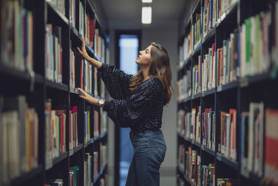 Full length of young woman reading book