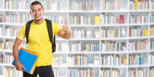 Portrait of smiling young man standing in shelf