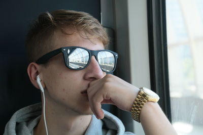 Close-up of man wearing sunglasses while traveling in train