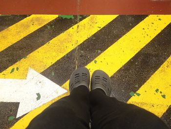 Low section of person standing on yellow road