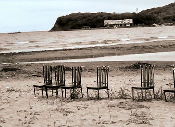 Deck chairs on sand at beach against sky