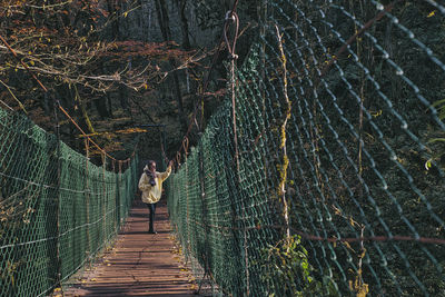 Rear view of people walking on footbridge in forest