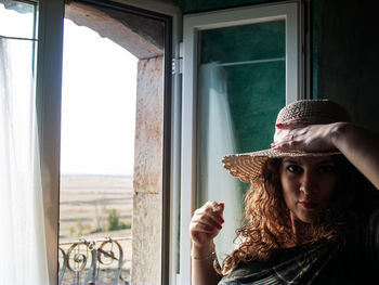 Portrait of smiling woman standing by window