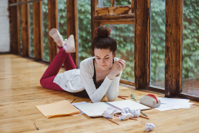 Woman reading book while lying on floor