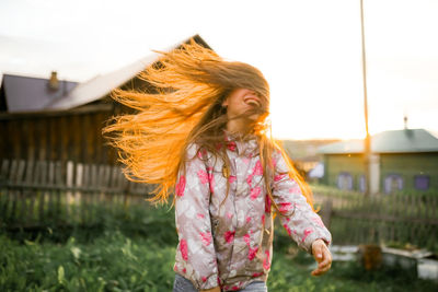 Portrait of girl with arms raised standing against sky