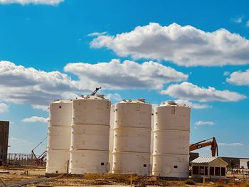 Low angle view of birds perching on factory against sky