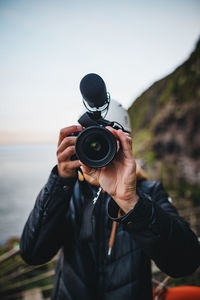 Man photographing with camera against sky