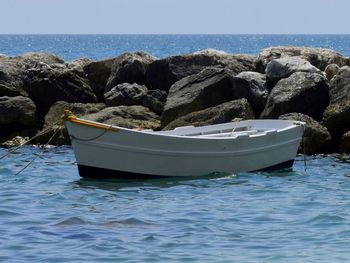 Boat on rocks by sea against sky