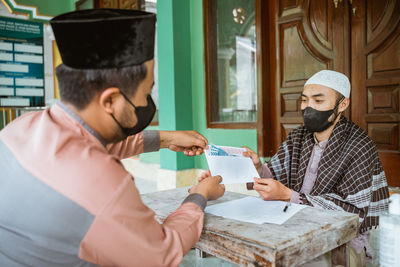 Young men wearing protective face mask sitting in mosque