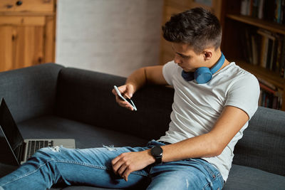 Man using mobile phone while sitting on sofa at home