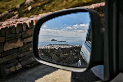 Reflection of sky on side-view mirror of car
