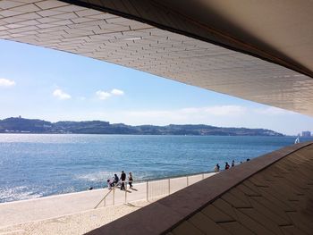 People on promenade by sea seen from bridge