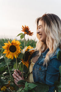 Portrait of woman with sunflower against plants