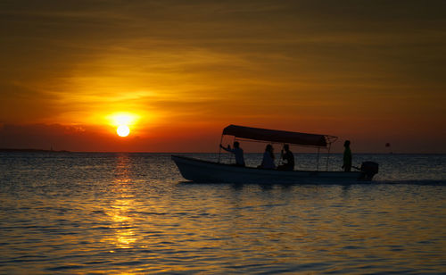 Silhouette boat in sea against orange sky