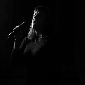 Young woman standing against black background