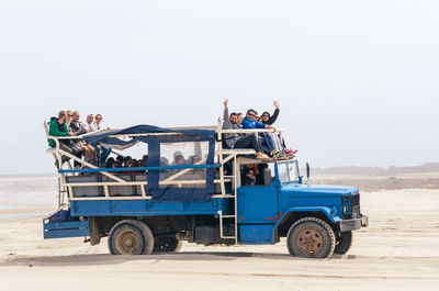 People sitting on land against clear sky