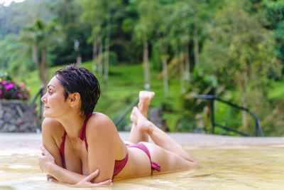 Side view of shirtless young woman sitting in swimming pool