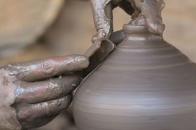 Cropped hands of potter shaping earthenware in workshop