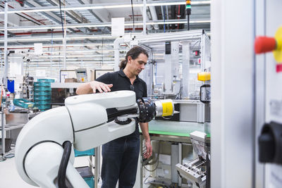 Man with assembly robot in factory