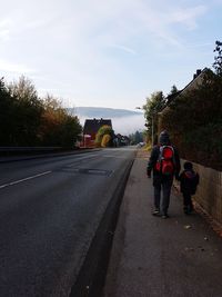 Rear view of people on road against sky