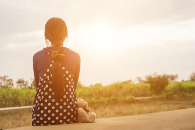 Rear view of woman standing against sky during sunset