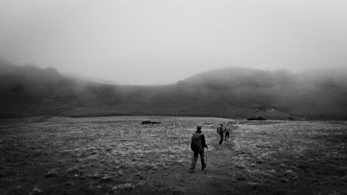 People walking on field against sky