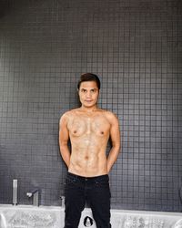 Portrait of shirtless man standing by swimming pool