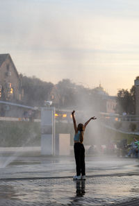 Rear view of woman standing against waterfall