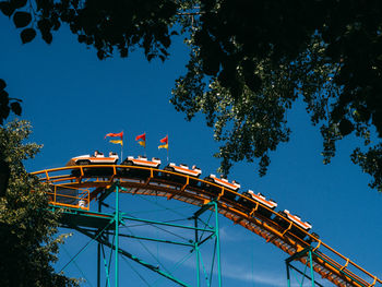 Low angle view of amusement park ride against blue sky