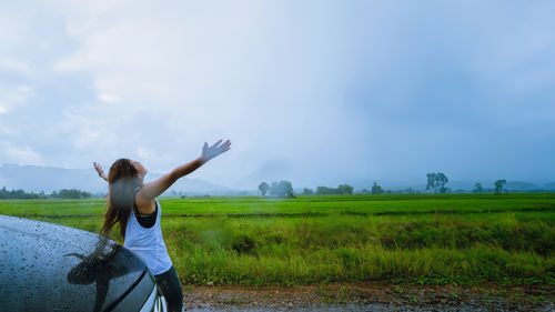 Rear view of woman standing on field against sky