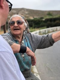 Senior woman talking with son while sitting on railing at roadside