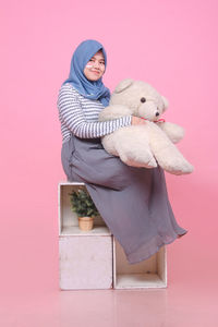 Portrait of woman with pink toy against gray background