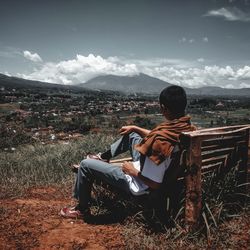 Man sitting on seat against cityscape