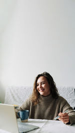 Side view of young woman sitting on white background