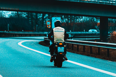 Rear view of man riding motorcycle on road