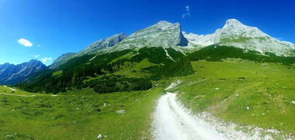 Low angle view of green mountain against blue sky